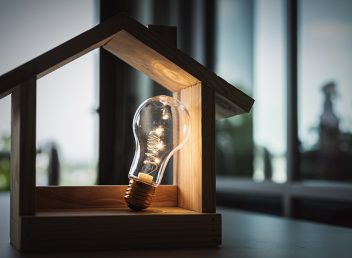 Light bulb with wood house on the table, a symbol for construction, Creative light bulb idea, power energy or business idea concept ecology, loan, mortgage, property or home.
